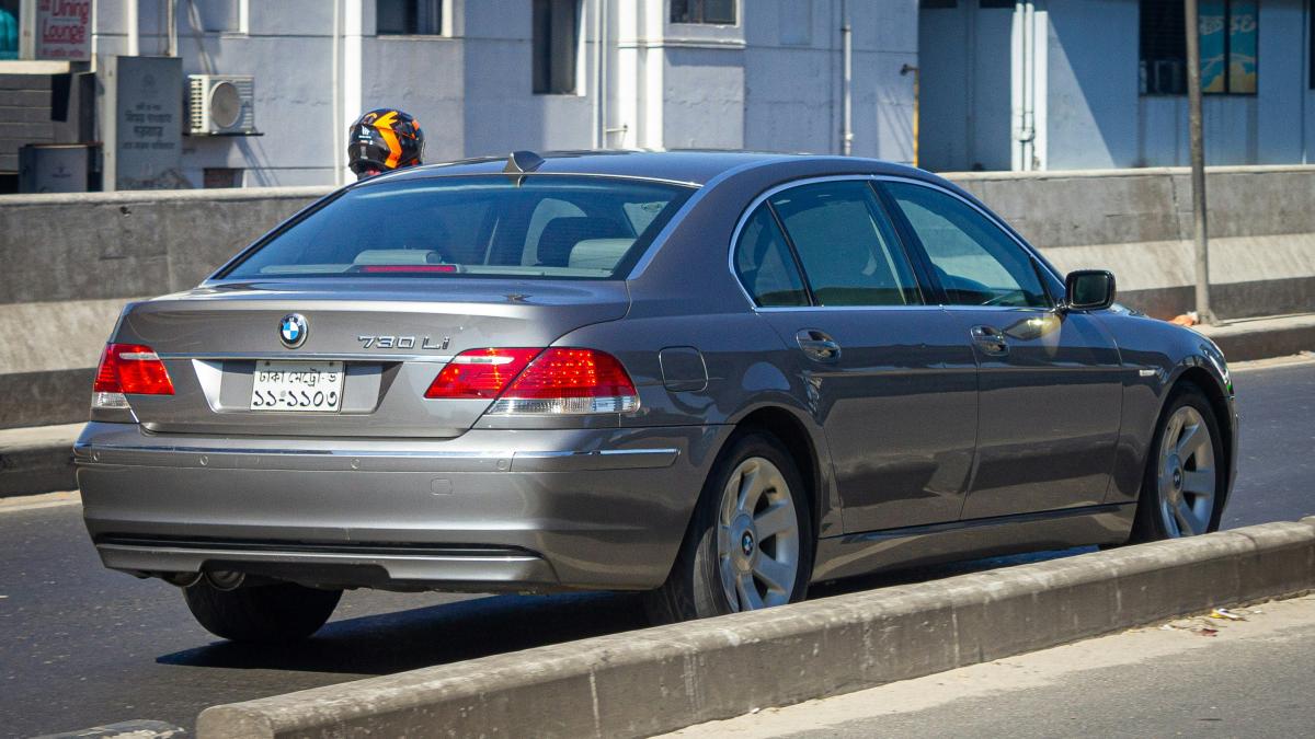 A silver car driving down a street next to tall buildings