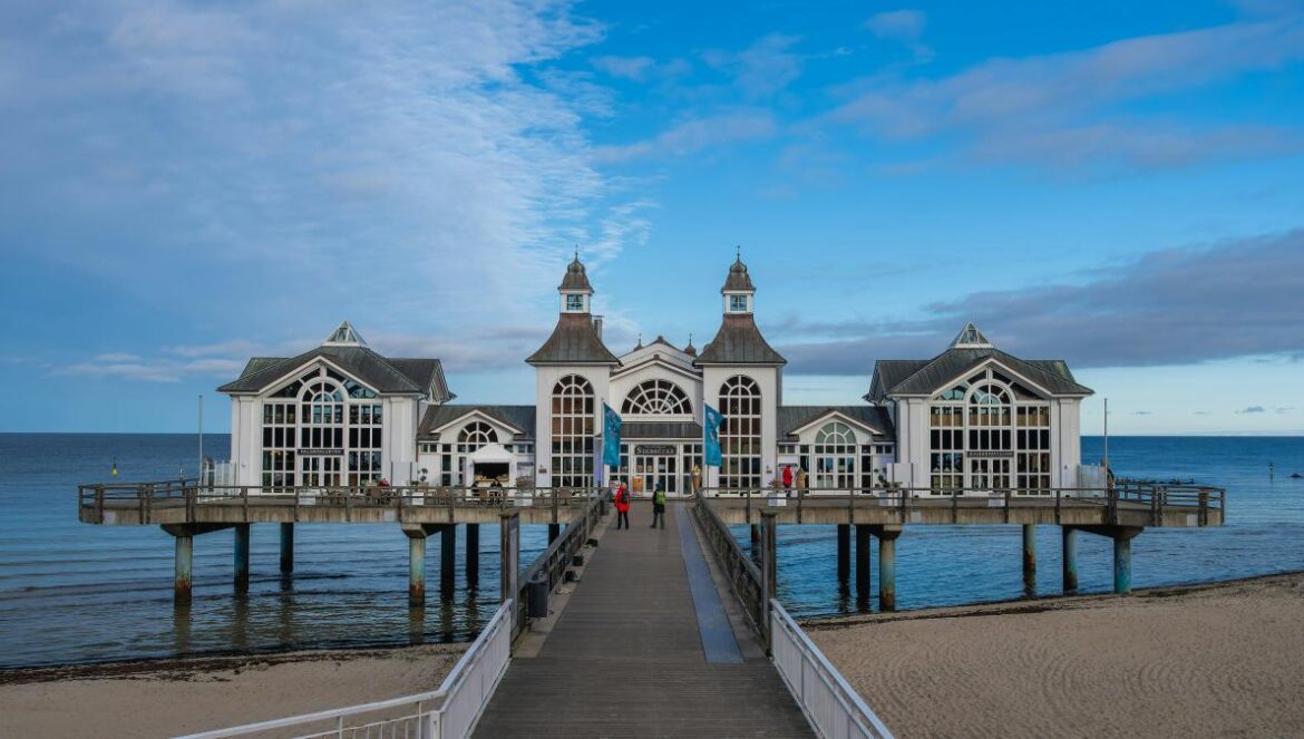 A pier on a beach with a building in the background