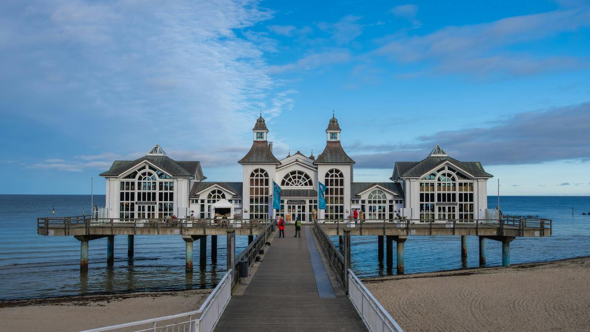 A pier on a beach with a building in the background