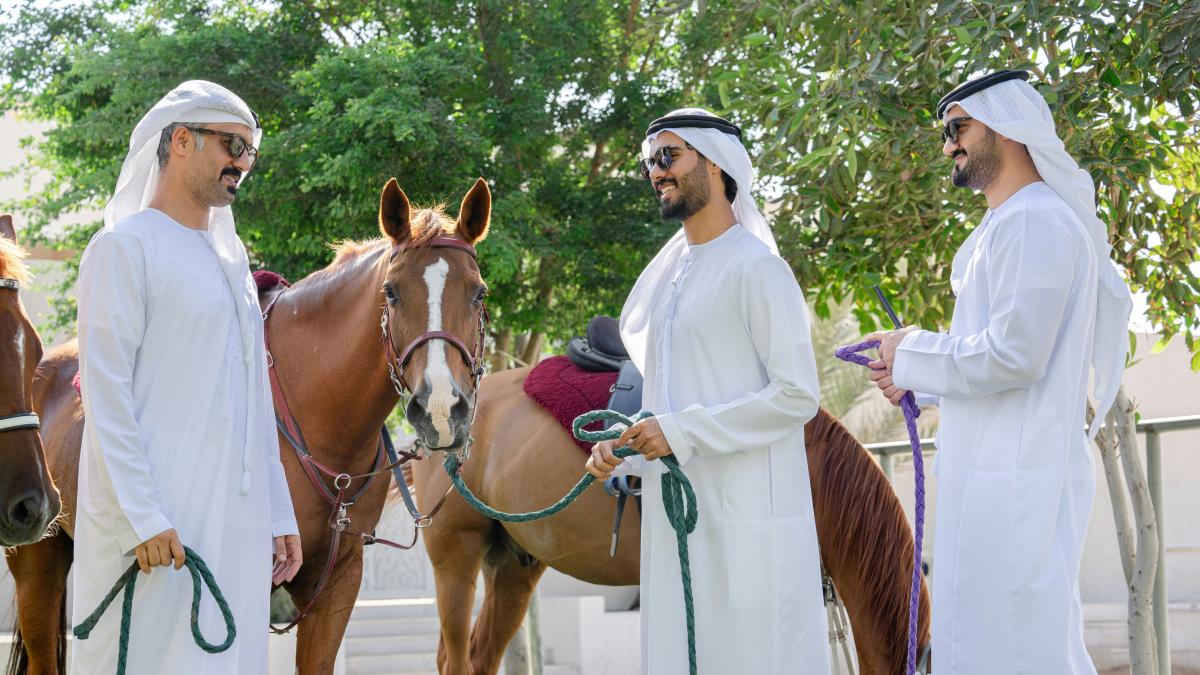 A group of men standing next to a brown horse