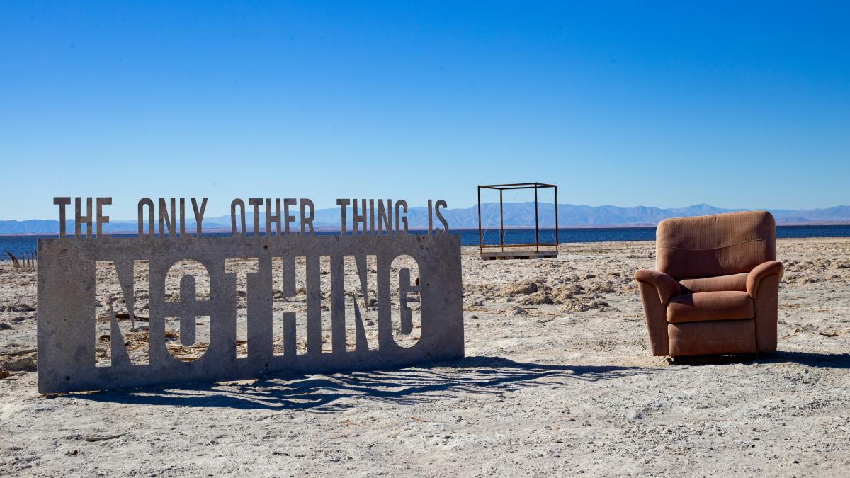 A chair and a sign sitting in the sand