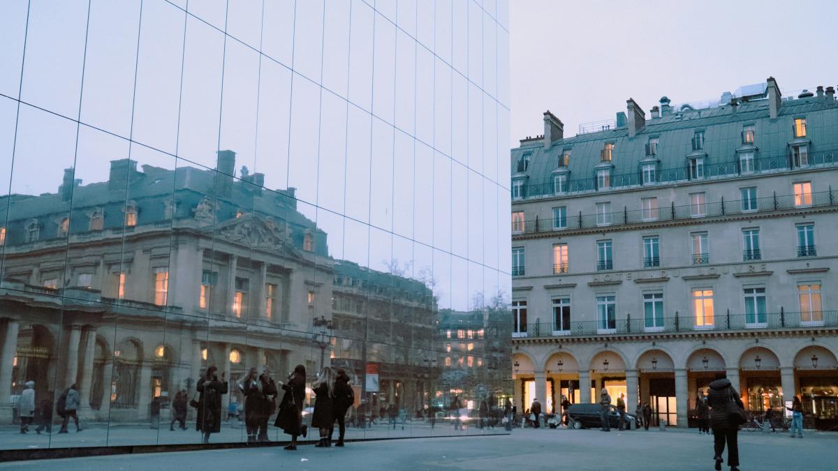 A group of people walking down a street next to tall buildings
