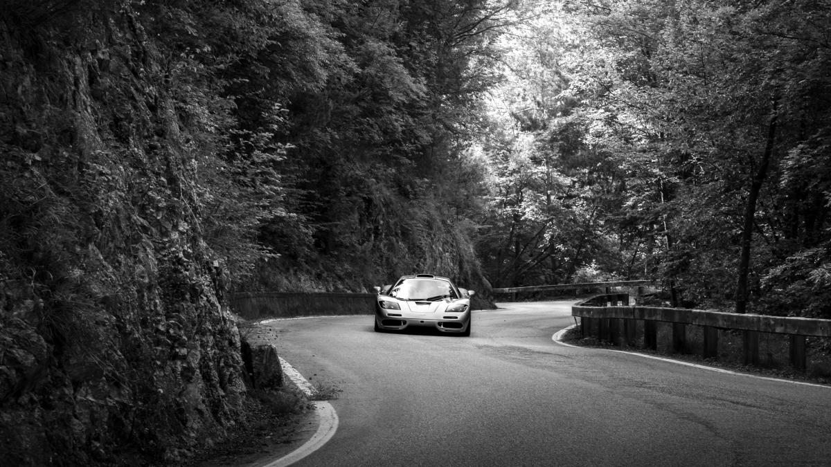 A black and white photo of a car driving down a road