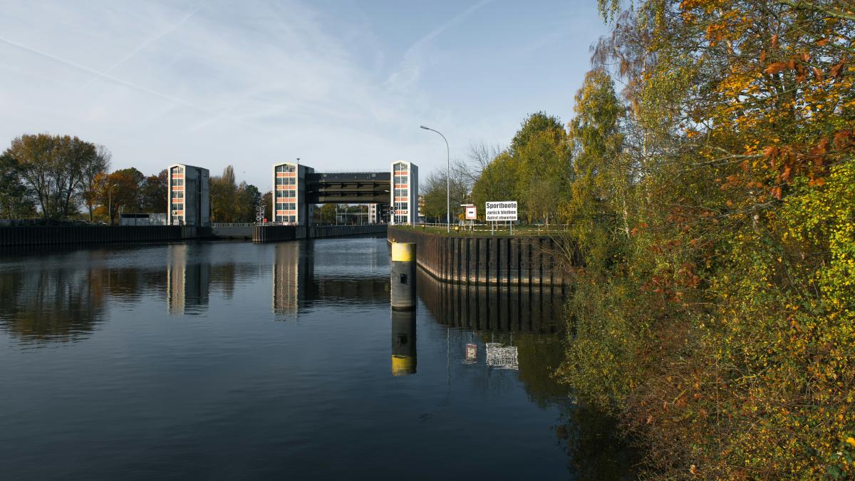 Water canal with industrial architecture and greenery.