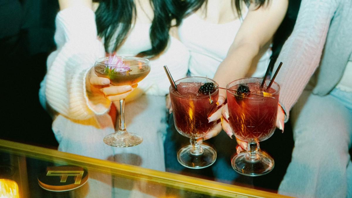 People are holding up cocktails in a close-up shot.
