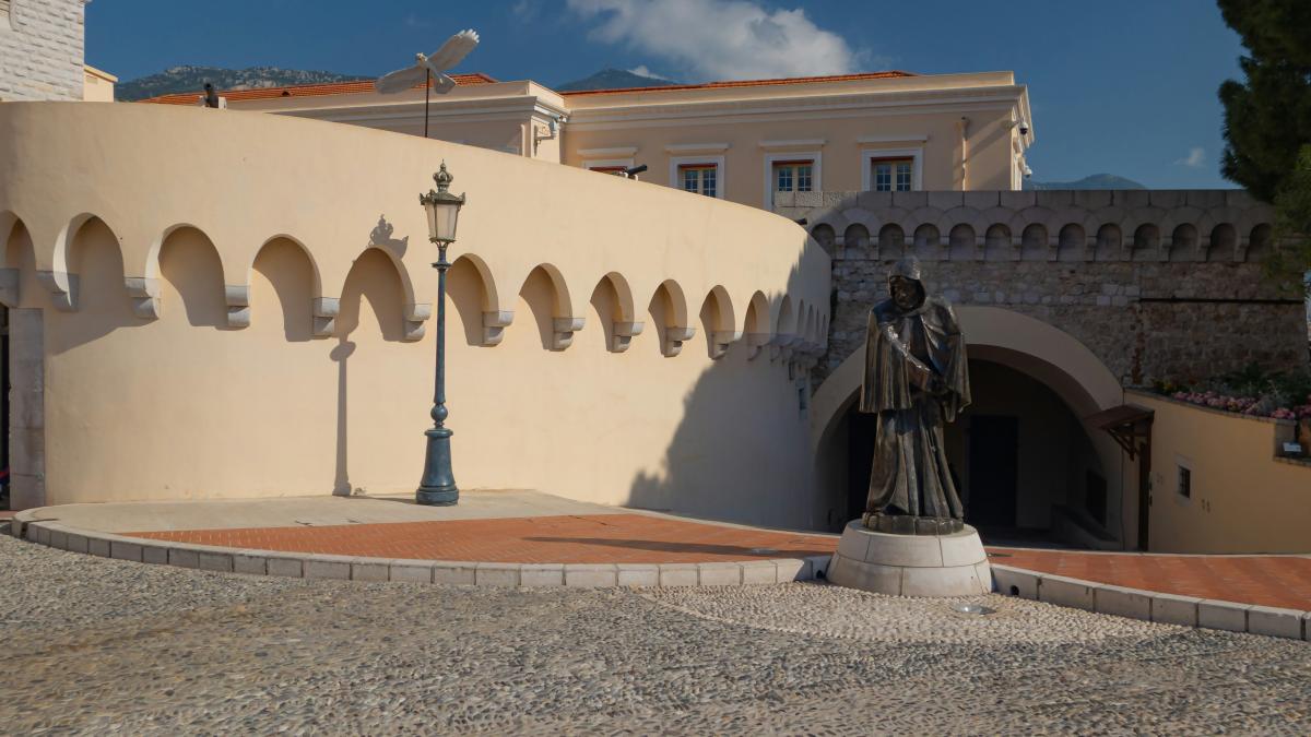 A statue sits near a building with arches.