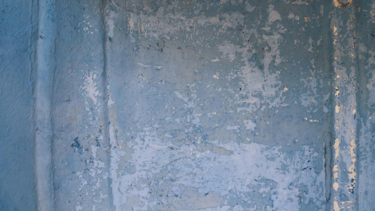 Weathered blue wall with peeling paint.
