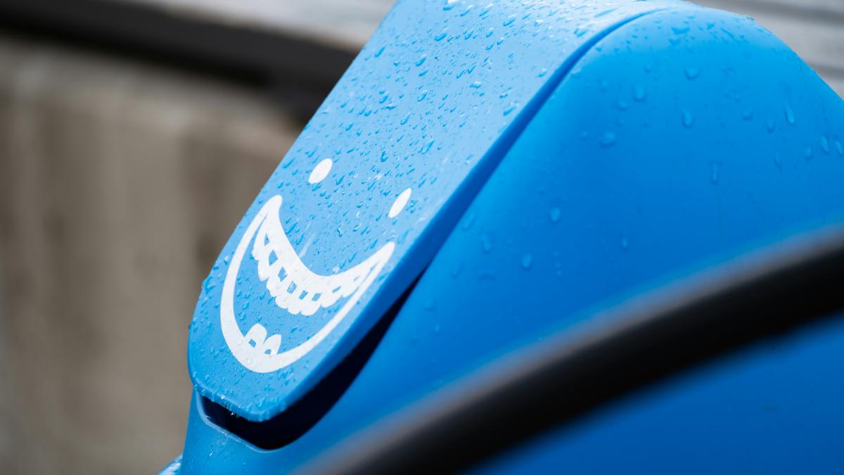 A blue trash can with a happy face.