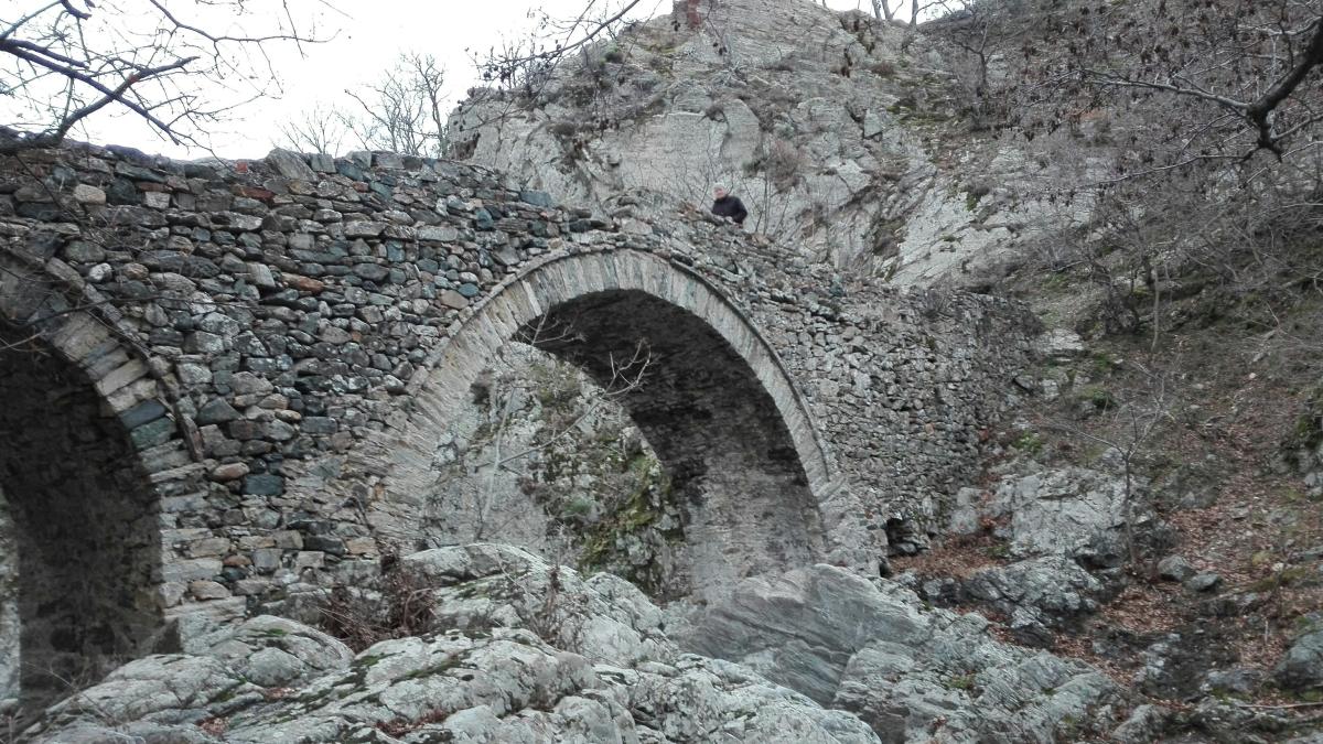 a stone bridge with a bird perched on top of it