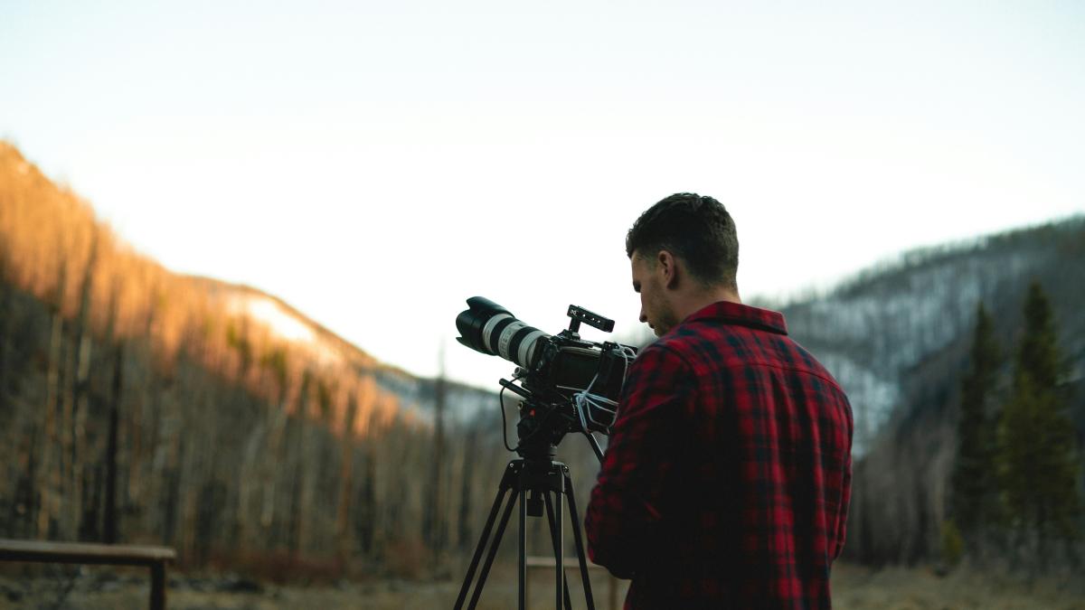 man in red and black plaid dress shirt standing on brown field during daytime