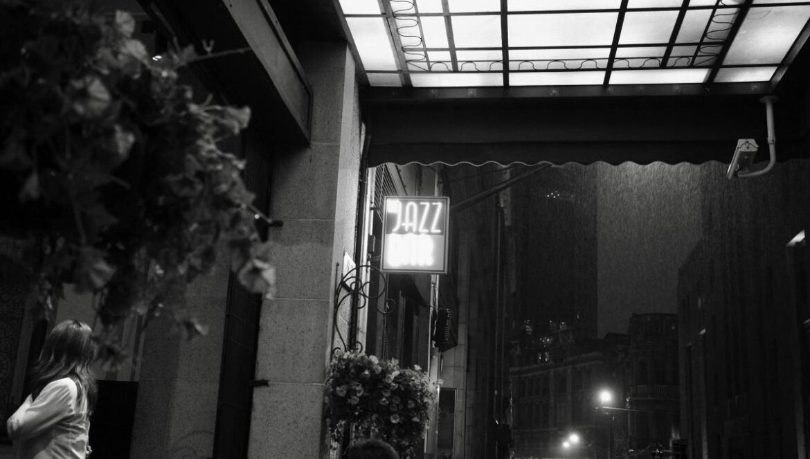 A jazz bar sign lights up a dark street.
