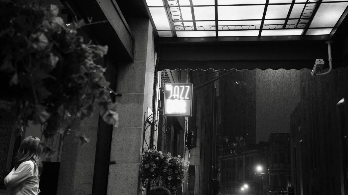 A jazz bar sign lights up a dark street.
