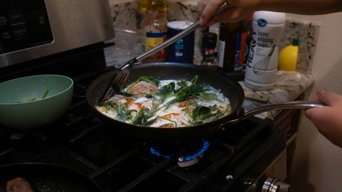 a person cooking food in a pan on the stove