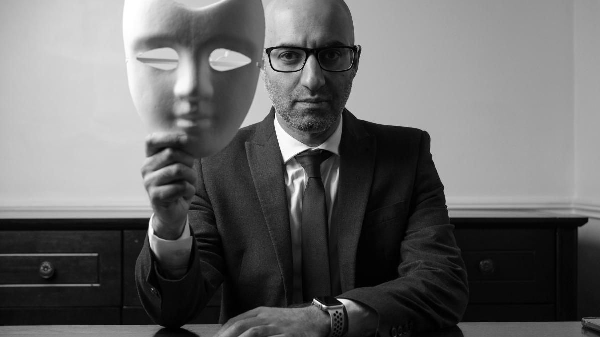 A man sitting at a table with a mask on his face