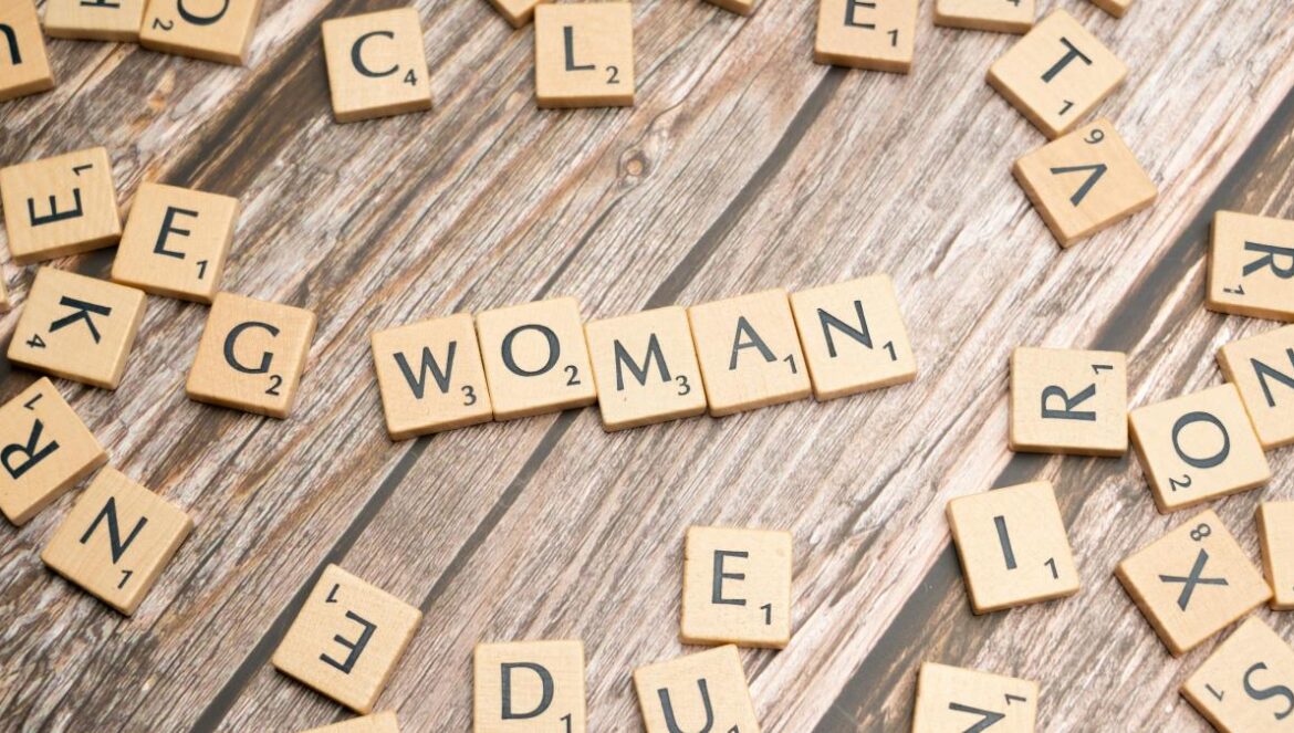 scrabble letters spelling women on a wooden surface
