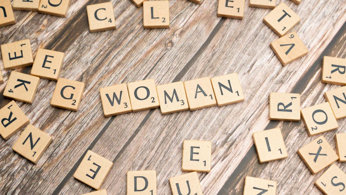 scrabble letters spelling women on a wooden surface