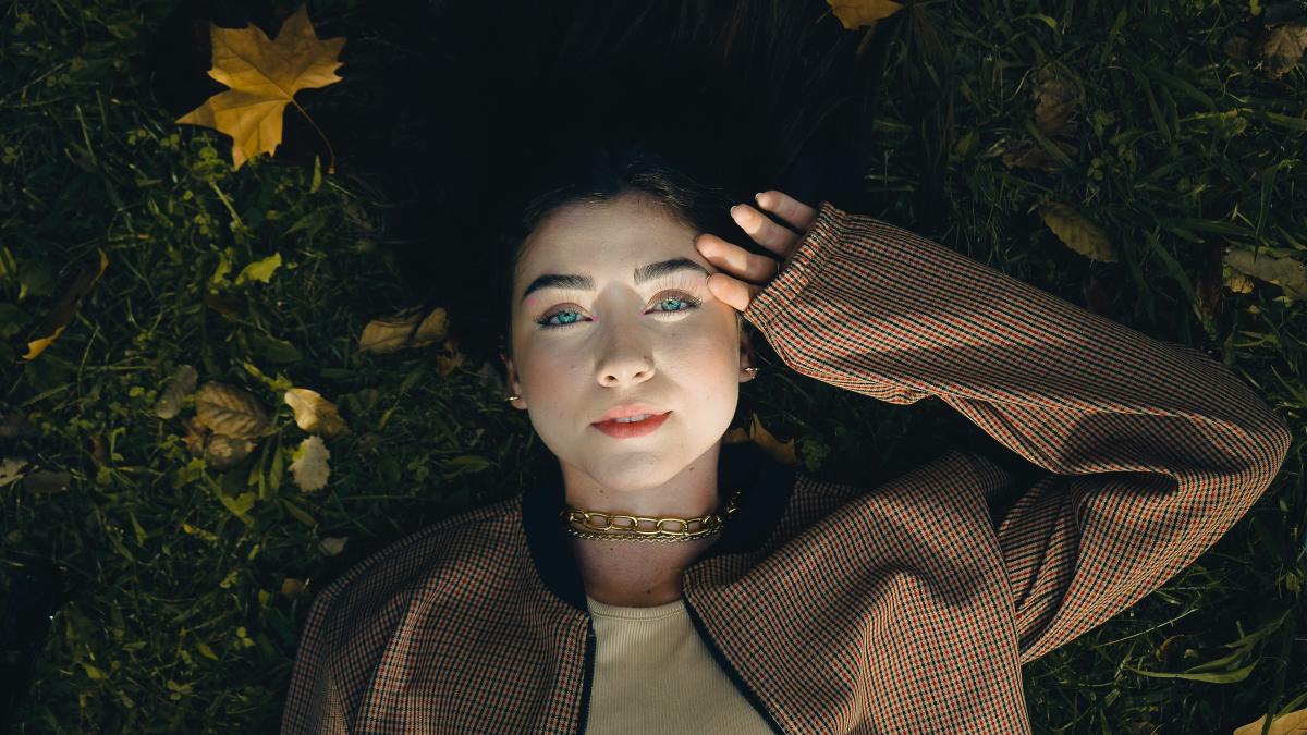 A woman laying in the grass with her hair blowing in the wind