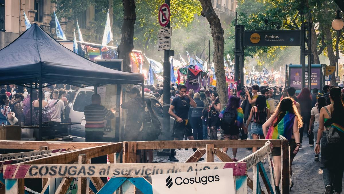 a crowd of people walking down a street next to tall buildings