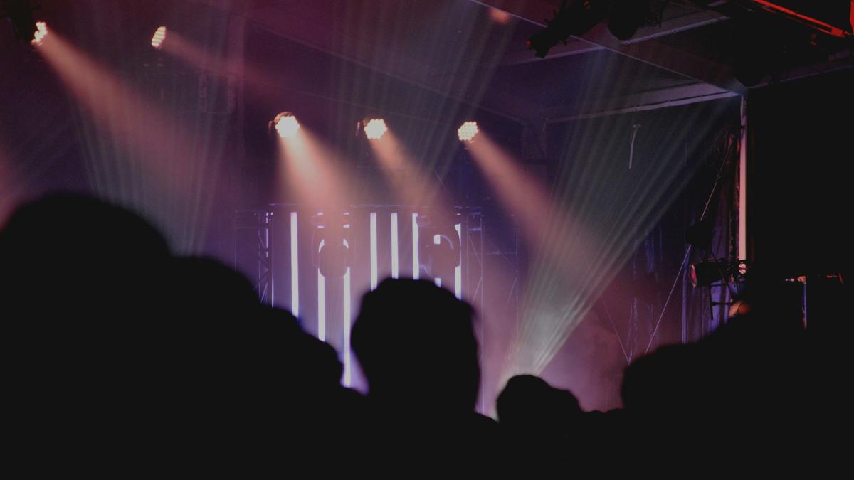 People are watching a concert with stage lights.