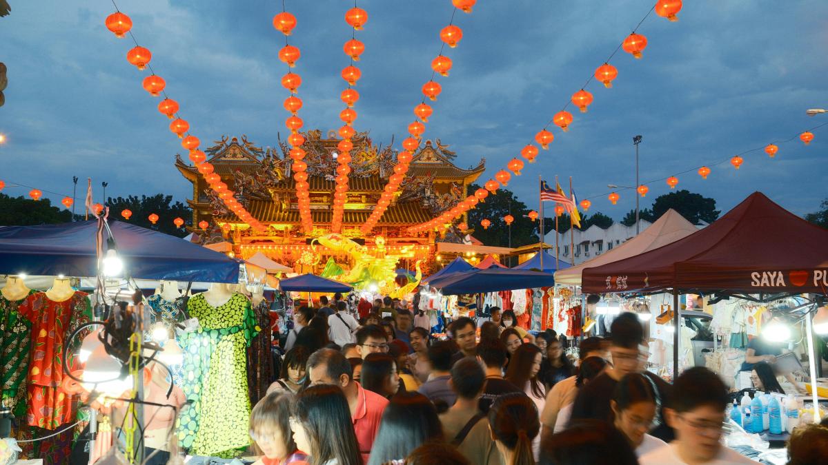 A crowd of people walking around a market