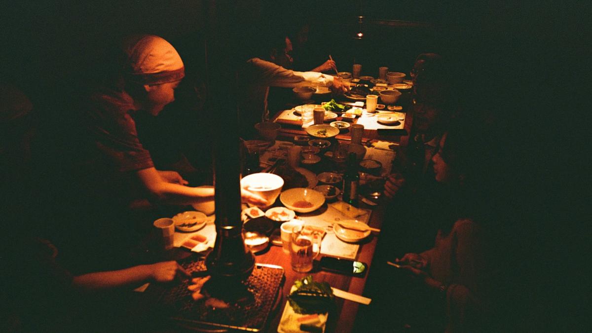 a group of people sitting at a table with plates of food