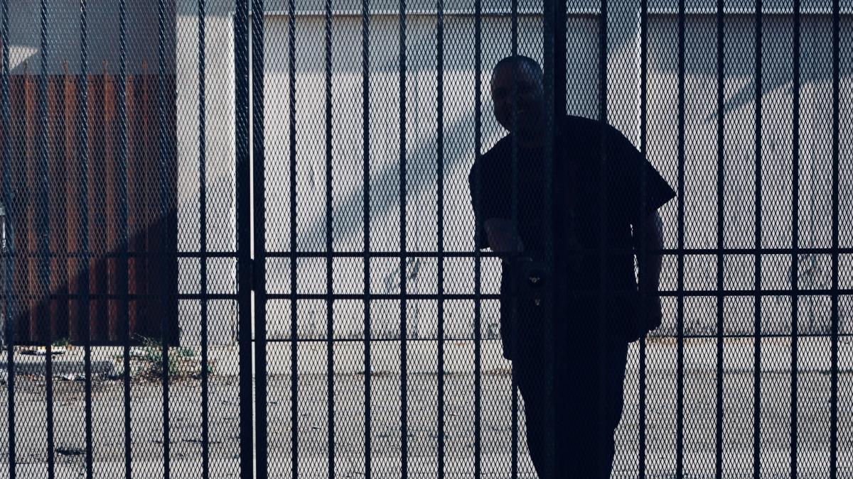 man trying to open metal gate during daytime