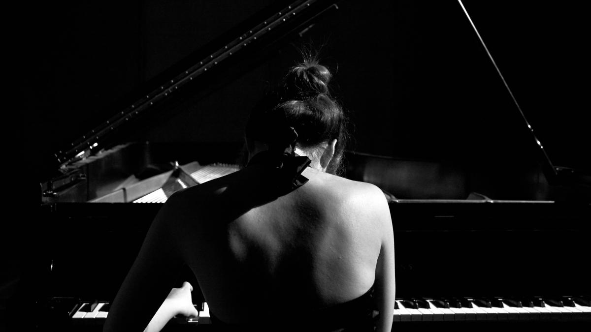 selective focus photography of woman playing grand piano