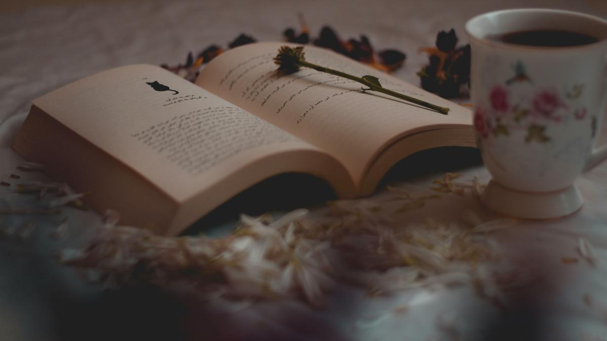 a cup of coffee and a book on a bed