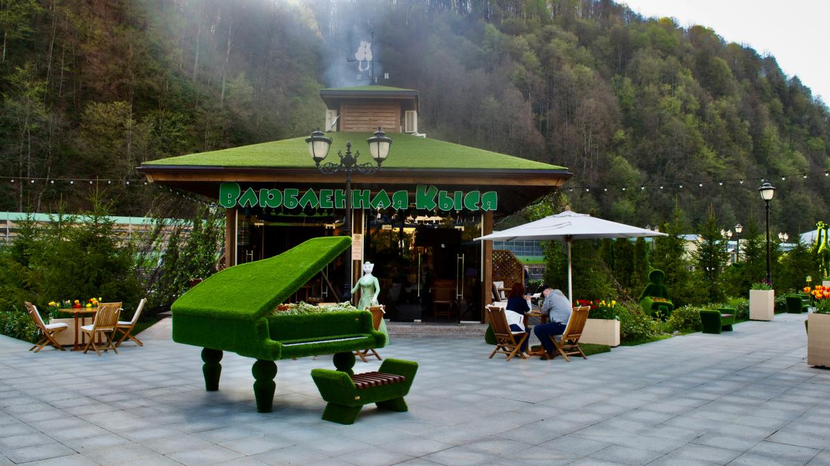 a group of people sitting outside a building with a mountain in the background