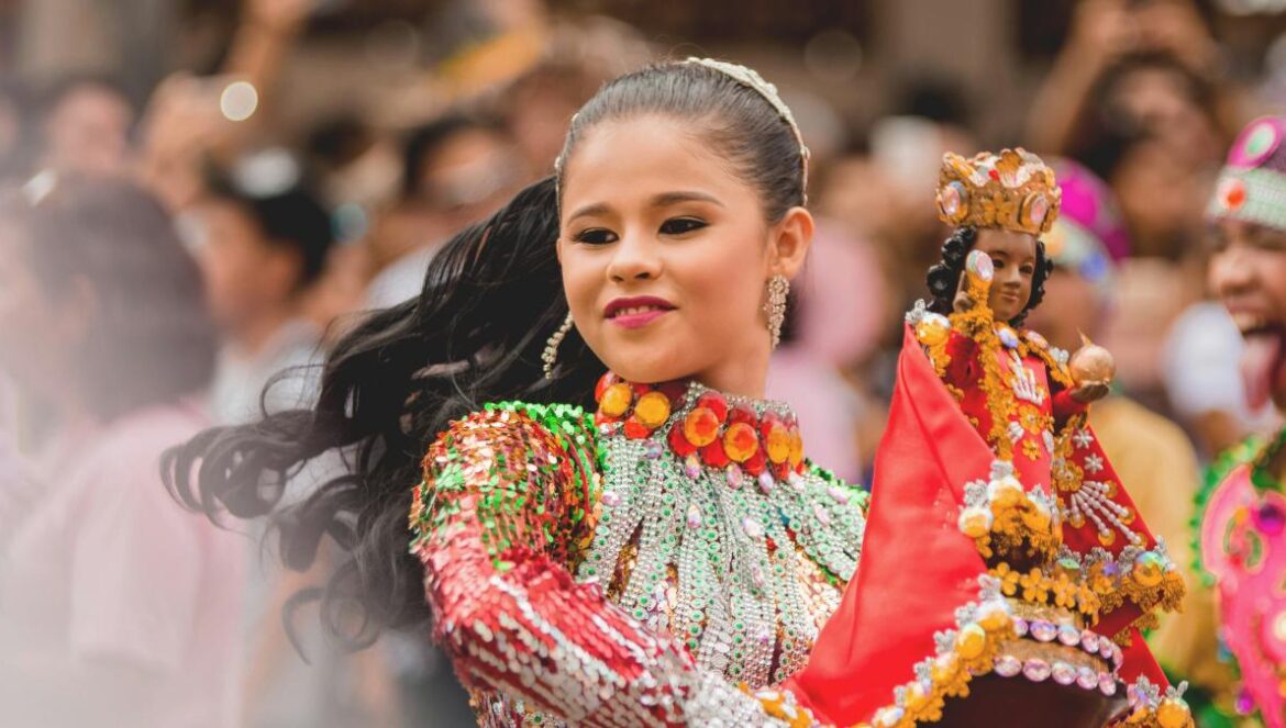 girl dancing while holding Sto.Nino figurine