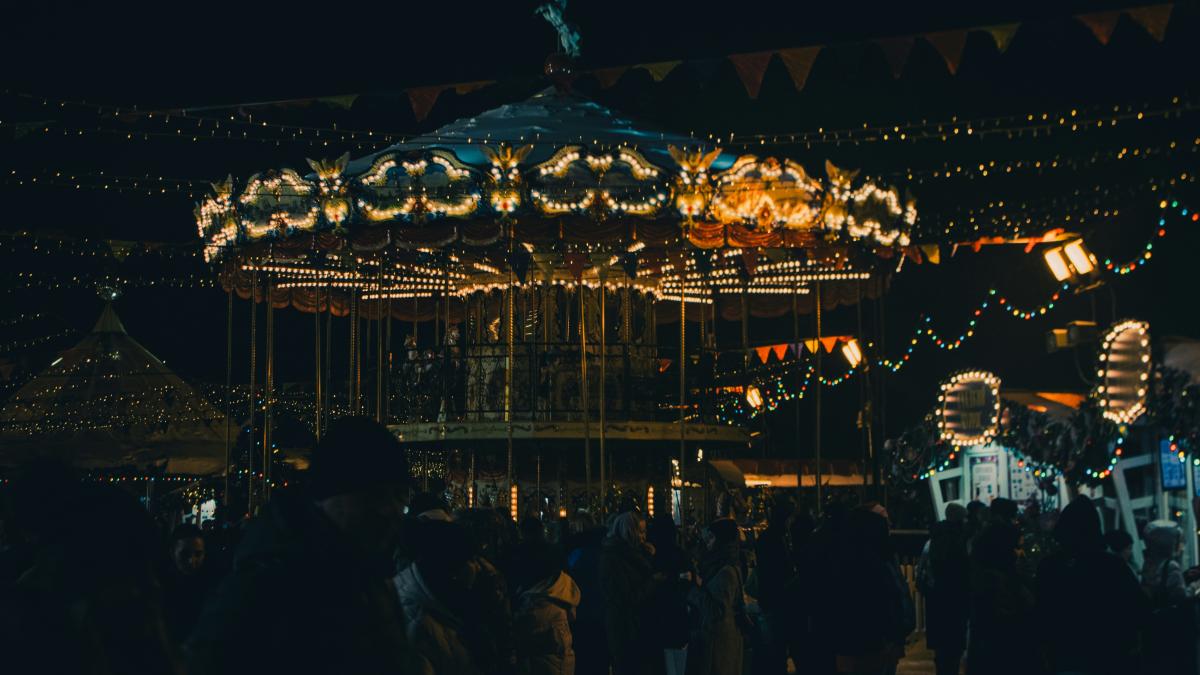 a crowd of people standing around a merry go round