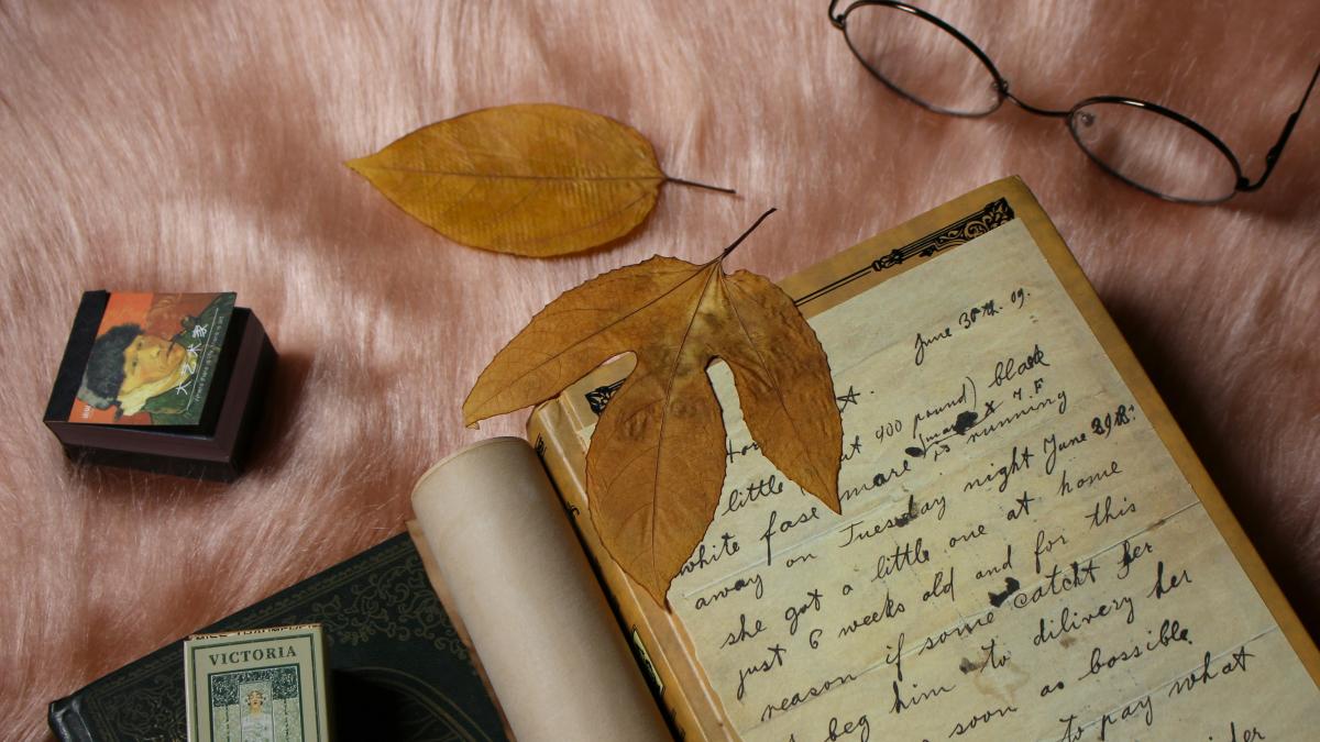 a book with a leaf on top of it next to a pair of glasses