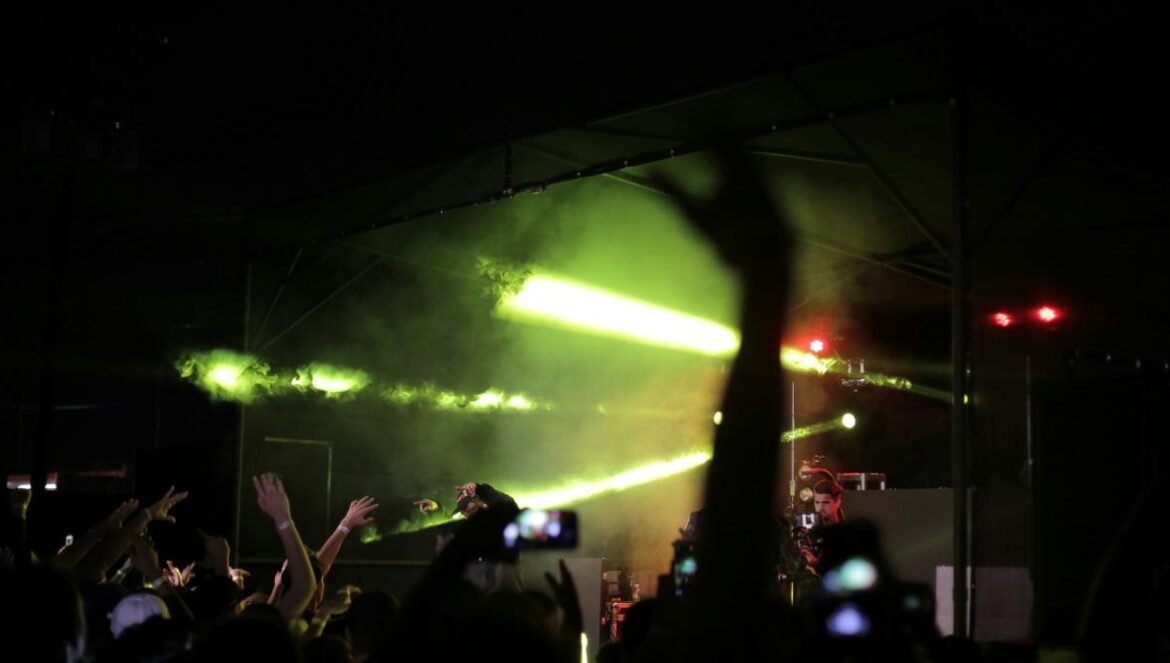silhouette of crowd raising hands fronting concert stage