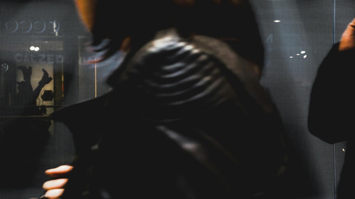 a woman in a leather jacket looking at her reflection in a mirror