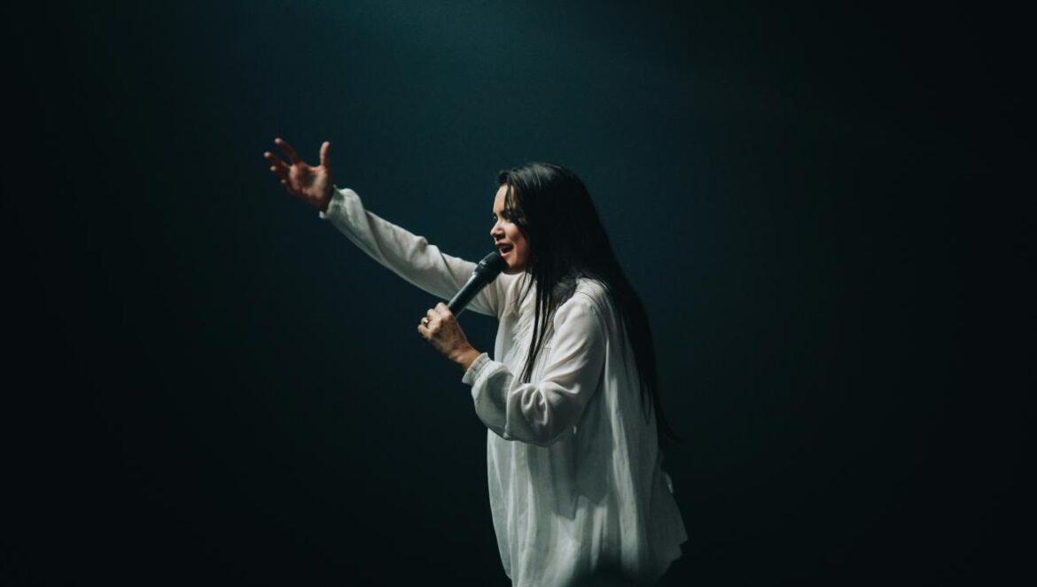 woman in long-sleeved shirt holding microphone