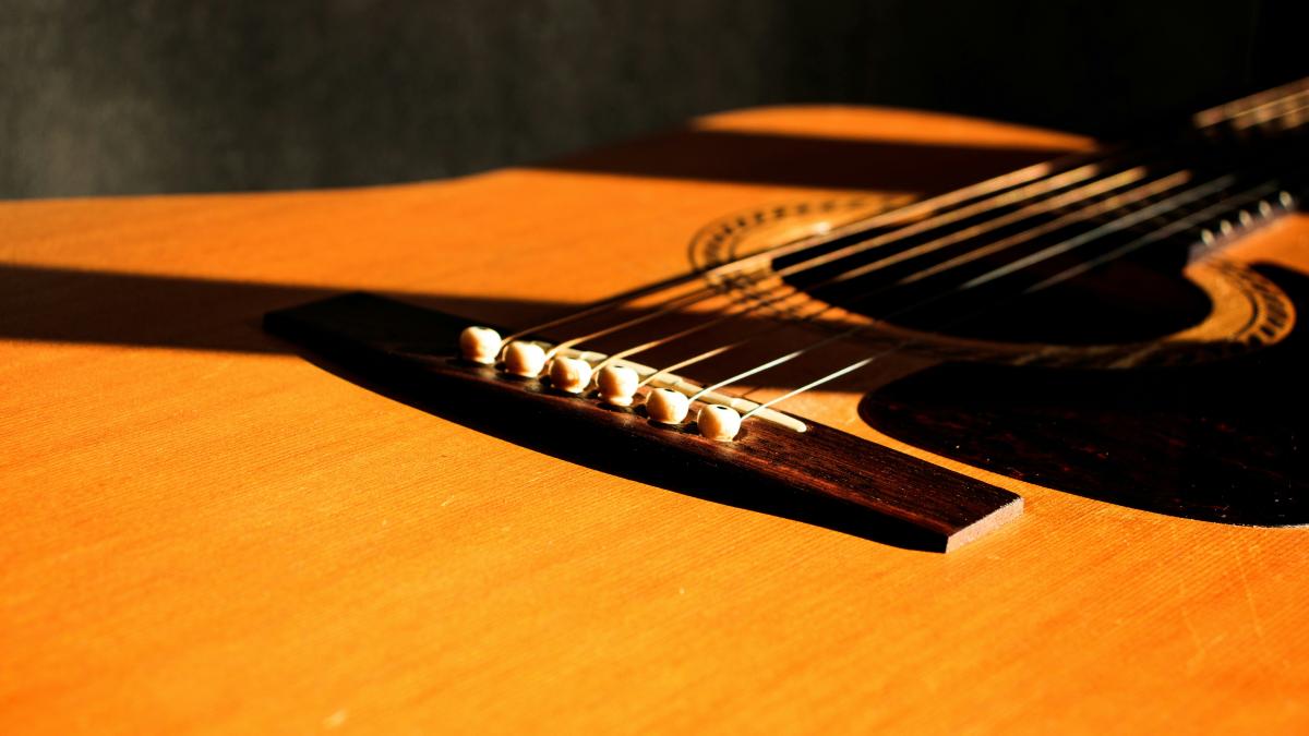 shallow focus photography of brown acoustic guitar