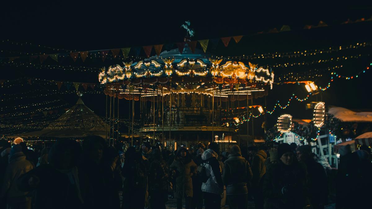 a crowd of people standing around a merry go round