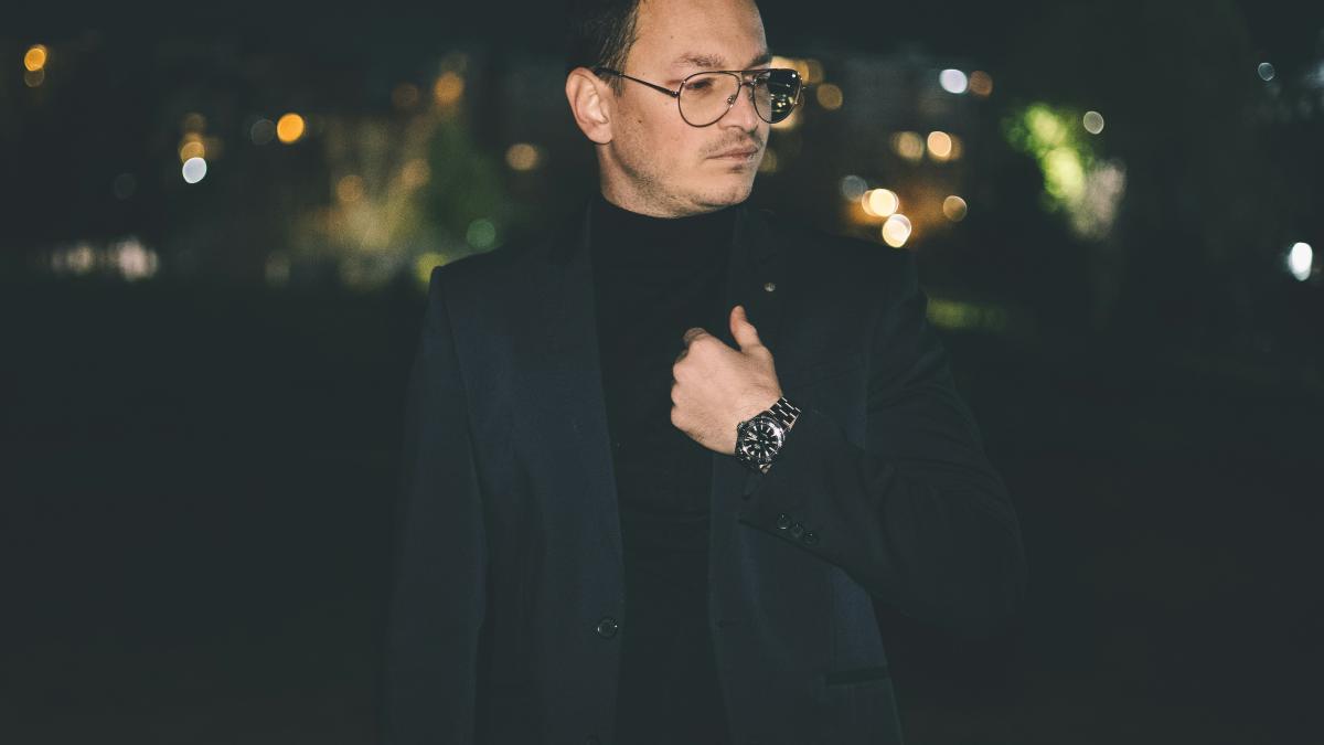 a man in a suit and glasses standing in the dark