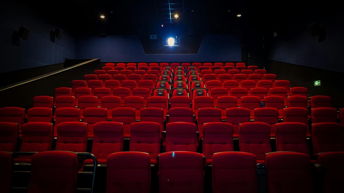 an empty theater with red seats and a projector screen
