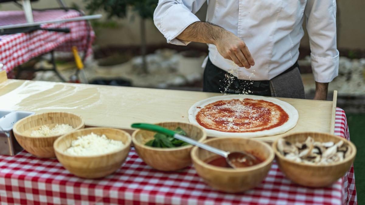 a man is sprinkling cheese on a pizza