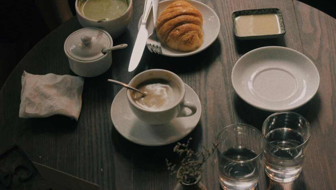 cup of coffee and bun of bread on table