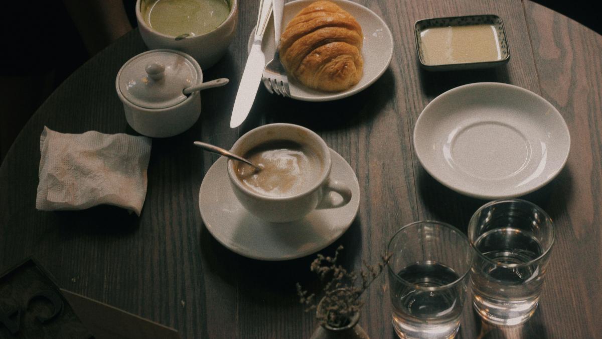 cup of coffee and bun of bread on table