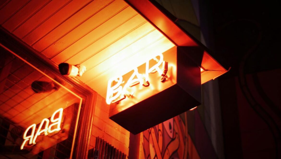 orange Bar signage beside bullet security camera