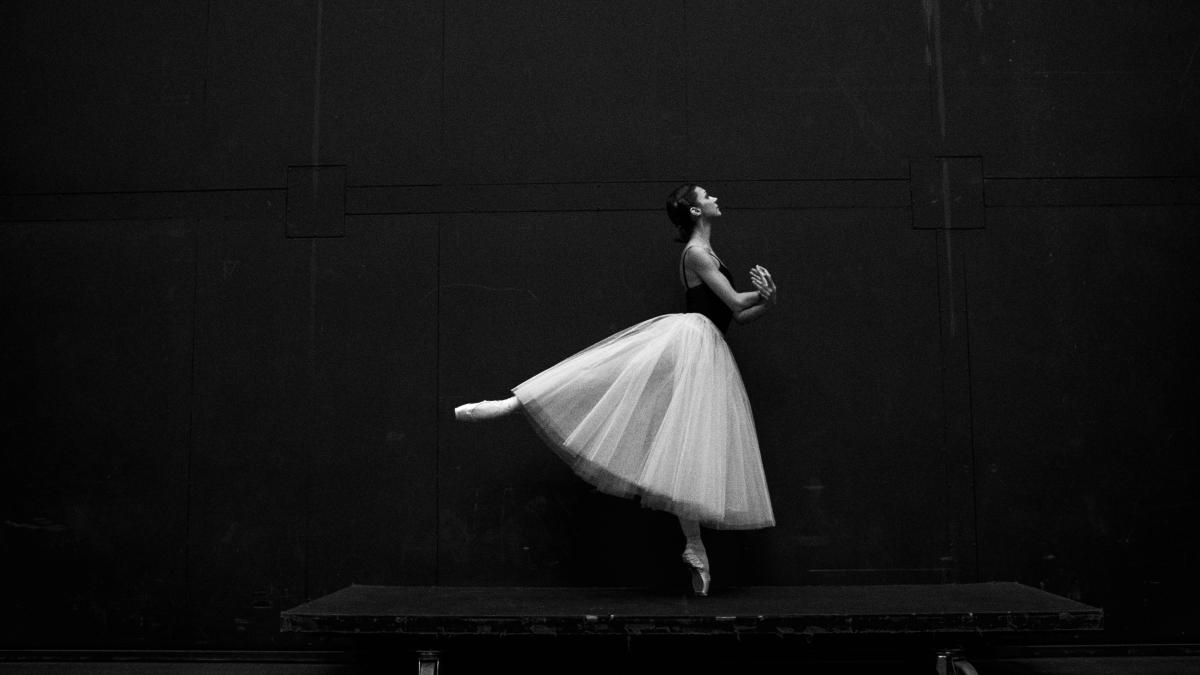 grayscale photography of ballet dancer standing on board