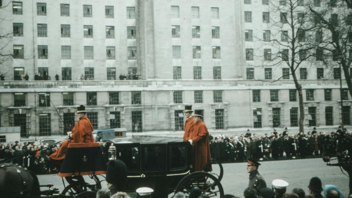 man in orange shirt standing on the street