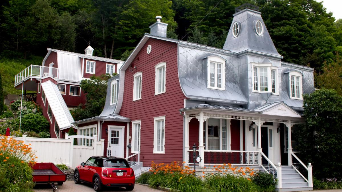 A red and white house with a red car parked in front of it