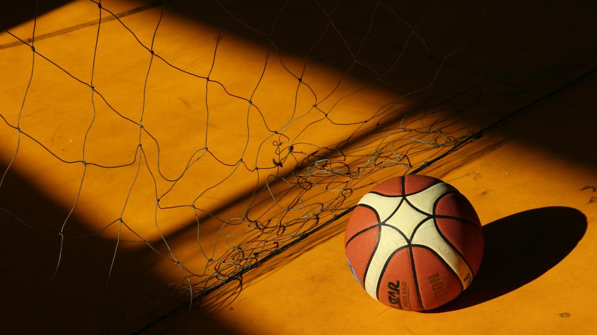 basketball near broken chain fence in dim light