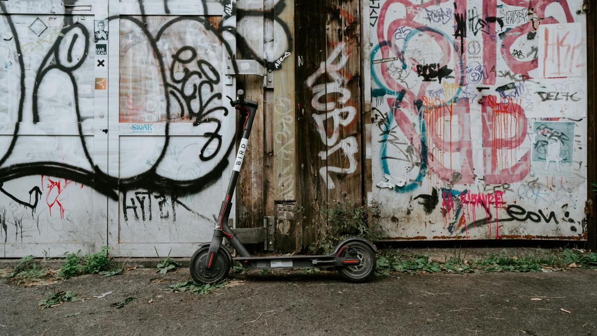 black kick scooter parked beside painted wall
