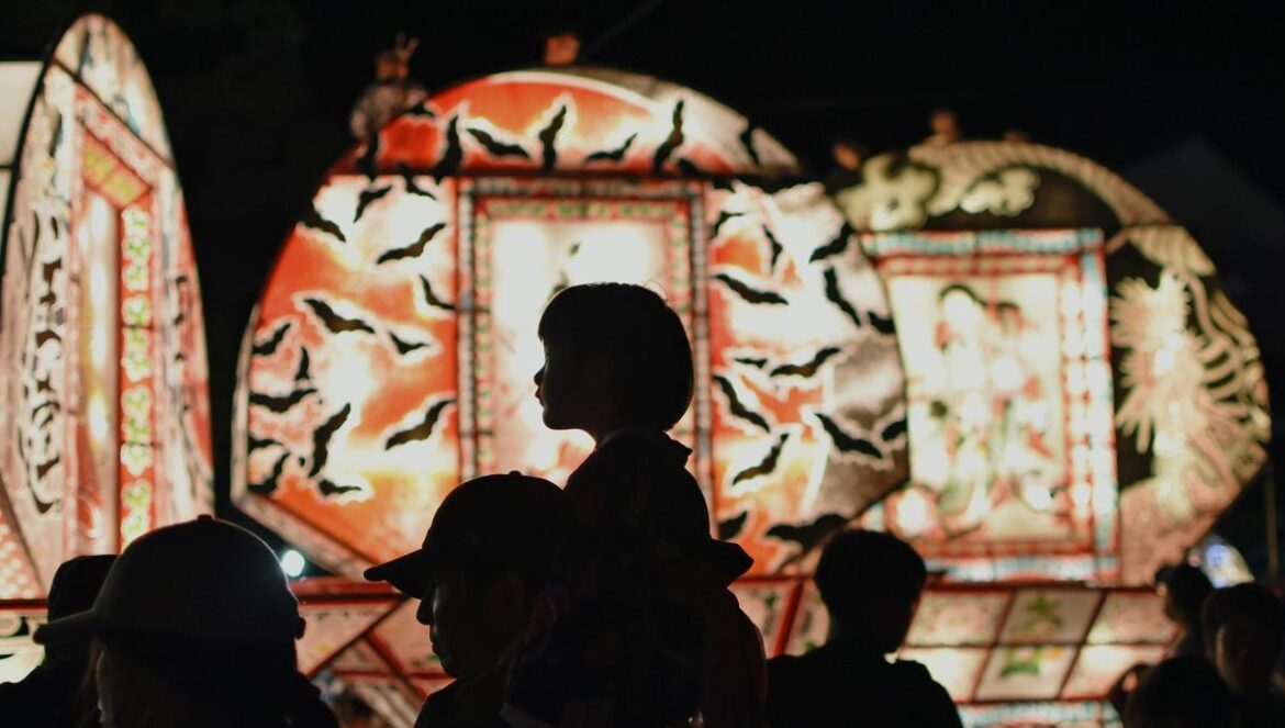 a crowd of people standing around a carnival ride at night