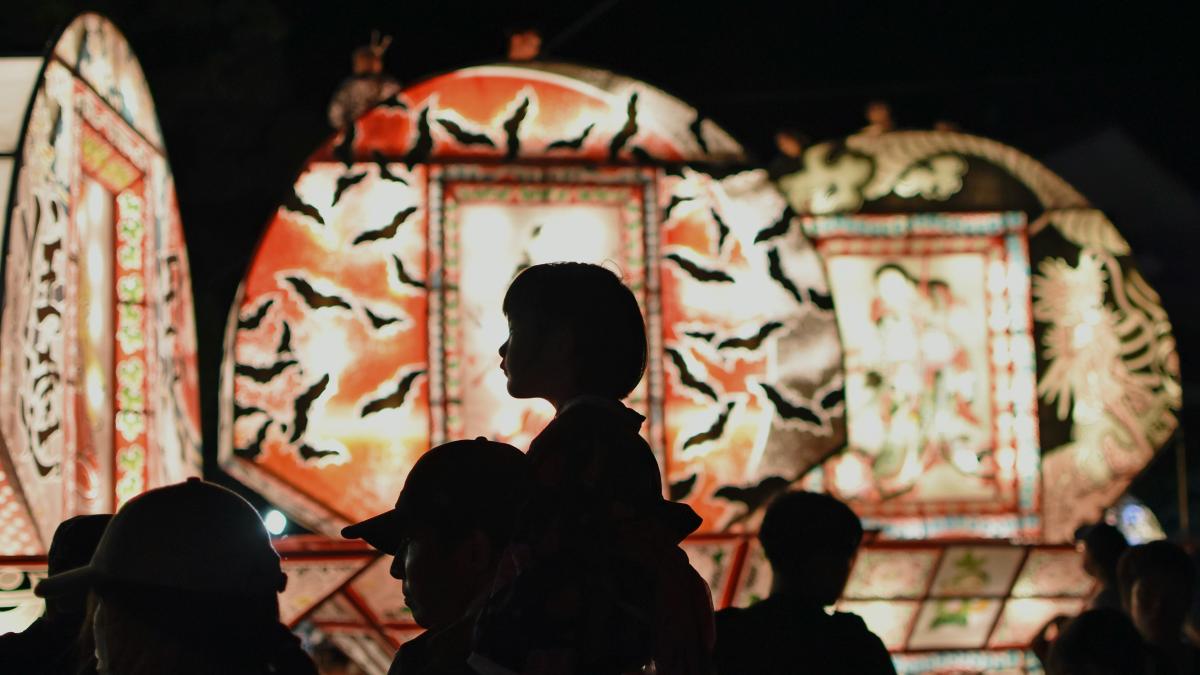 a crowd of people standing around a carnival ride at night